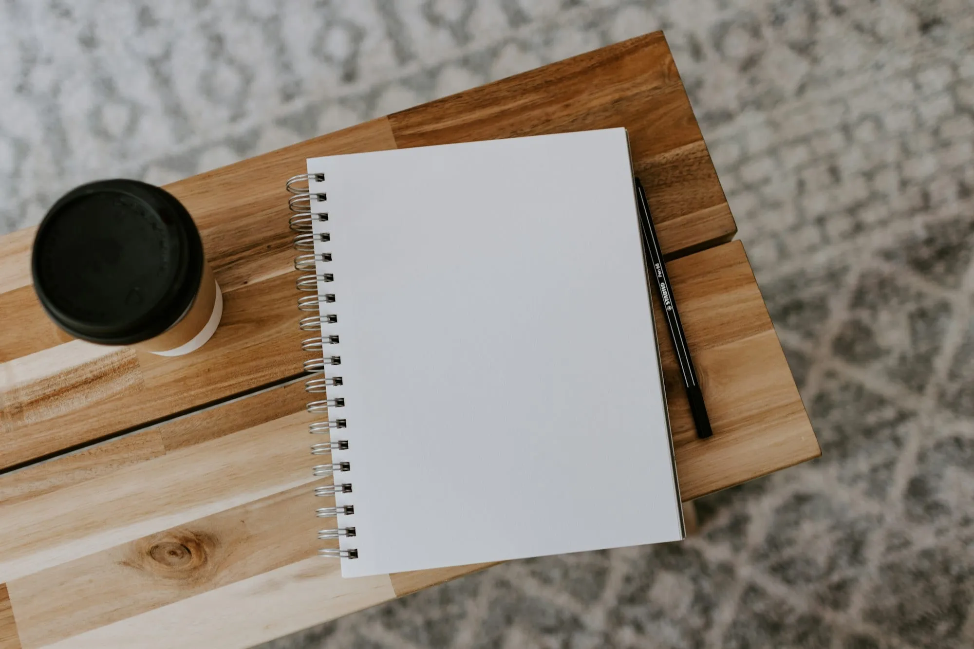 An open notebook and a cup of coffee on a wooden desk